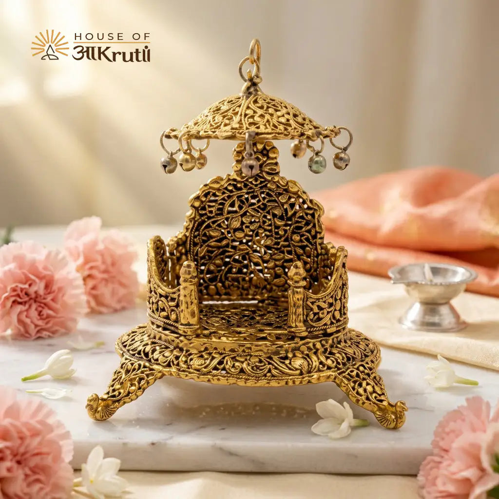 Decorative gold singhasan on a marble surface with pink flowers and a blurred background