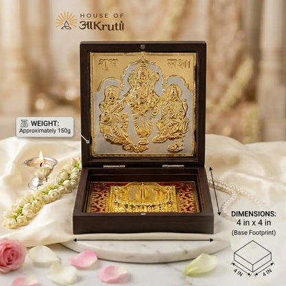 Decorative item in a wooden box with gold figures, surrounded by flowers and candles, on a soft background.